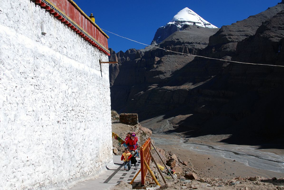 13 Tibetan Mother And Two Children Circumambulate Chuku Nyenri Gompa On Mount Kailash Outer Kora A Tibetan mother carries one child on her back while her son accompanies her on a circumambulation of Chuku (Nyenri) Gompa with Mount Kailash in the background.